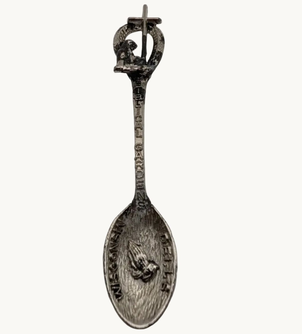 Souvenir spoon with raised cherub figure on oval bowl and ornate loop handle