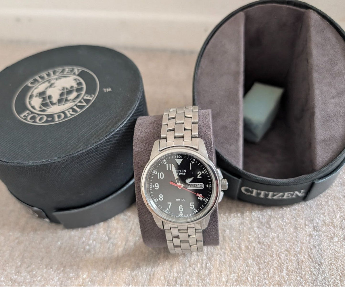 Military style watch with dark dial, steel bracelet, day-date display