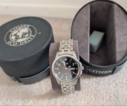 Military style watch with dark dial, steel bracelet, day-date display