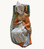 Reclining porcelain sultan figurine with painted turban, orange robe, and patterned cushions