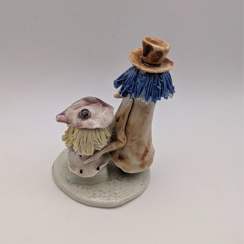 Pottery couple figurine, side view: blue tassel hat figure with seated partner