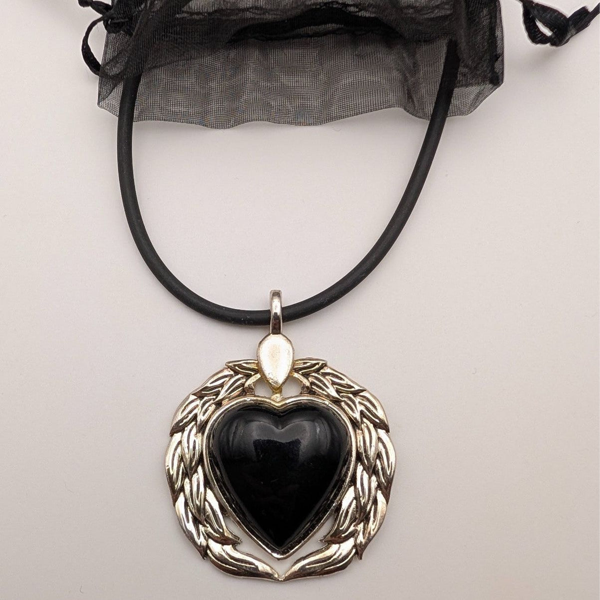 Black heart pendant necklace with winged silver-tone frame on black cord