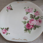 Porcelain dinner plate with pink rose bouquets and green leaves, gold rim accents