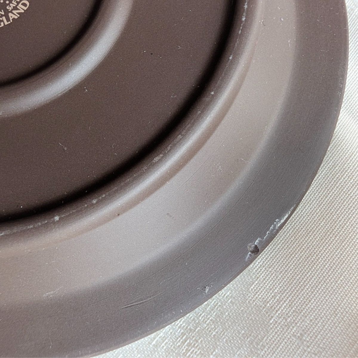 Stoneware plate rim close-up with smooth glazed edge and subtle speckling