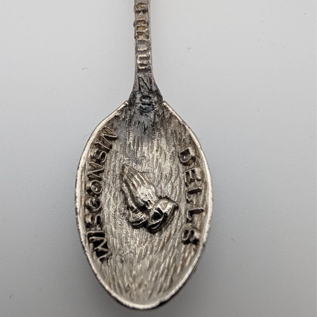 Souvenir spoon close-up of engraved oval bowl with cherub figure and surrounding text
