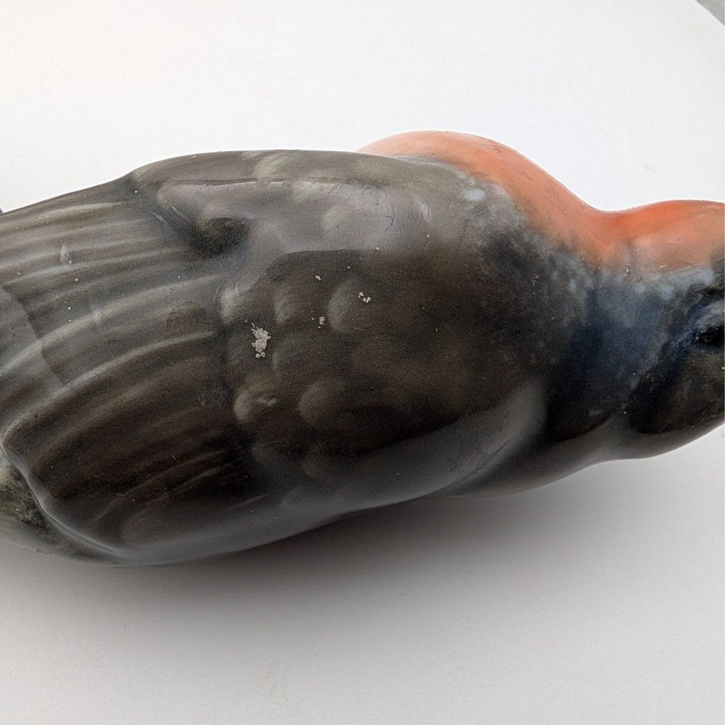 Close-up of hand-painted porcelain robin figurine, orange chest and gray wing details