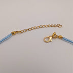 Gold clasp and chain on light blue beaded choker necklace