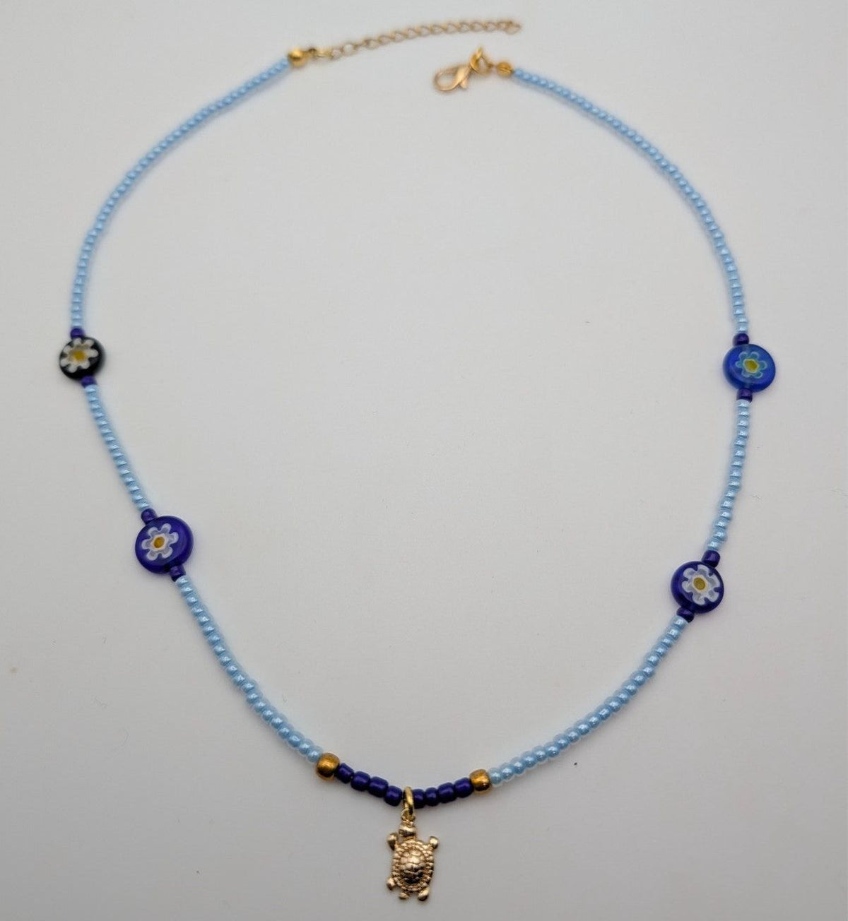Light blue beaded choker with blue flower beads and gold turtle charm