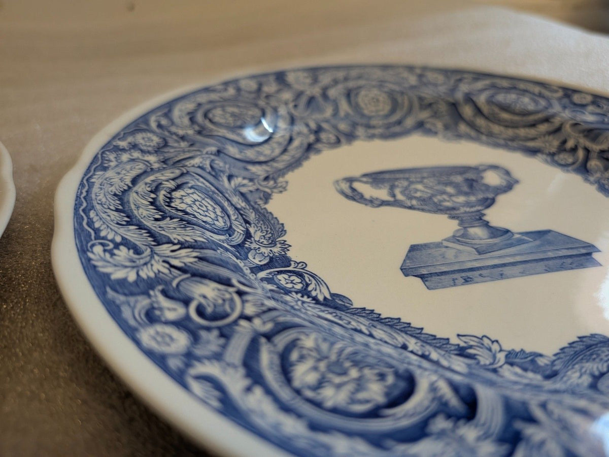 Blue-and-white dinner plate with detailed baroque scroll border and urn motif.