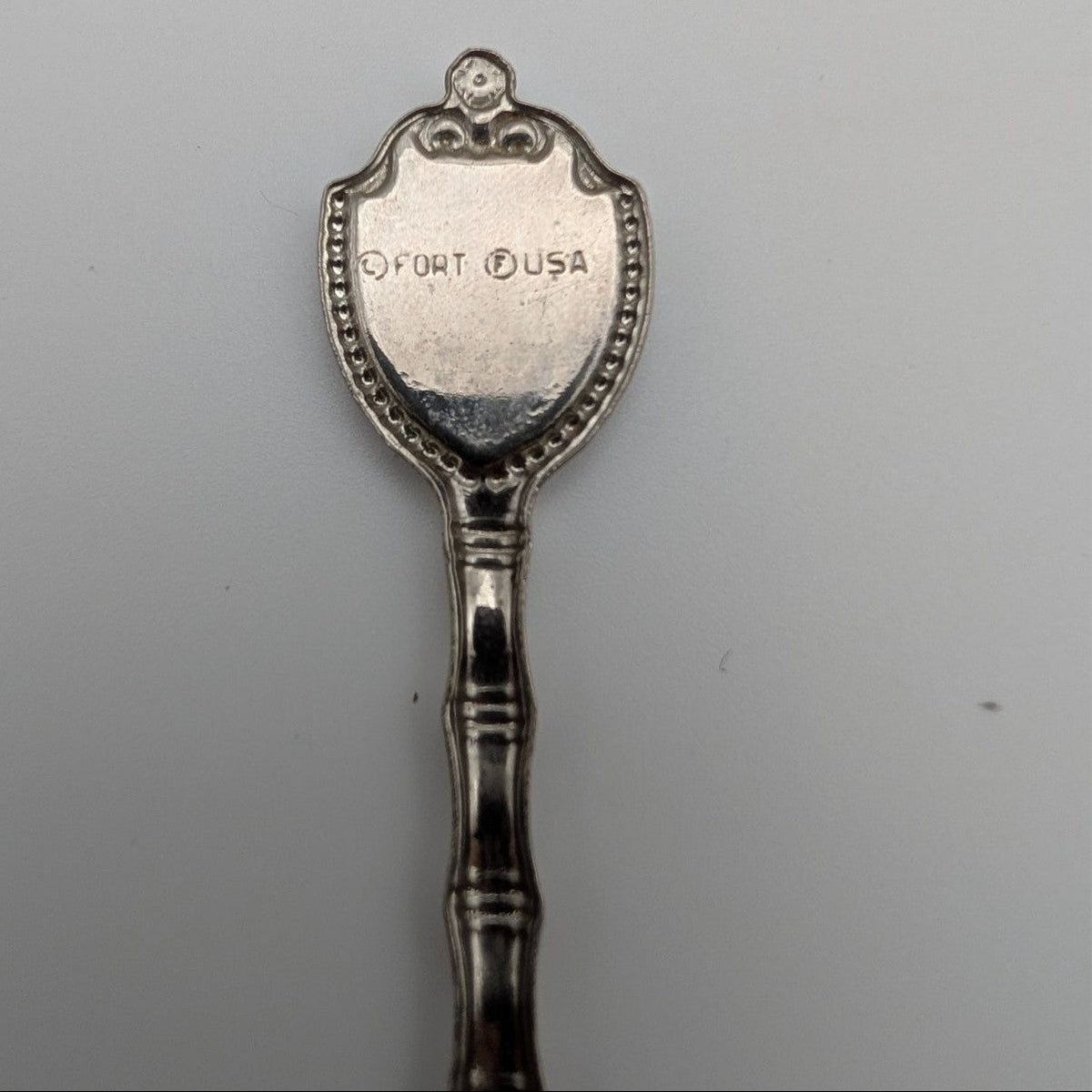 Souvenir metal spoon with engraved 'FORT USA' on back of oval crest
