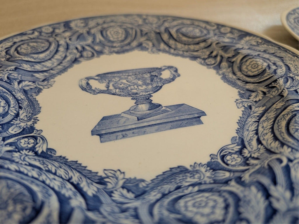 Blue-and-white dinner plate center design with urn illustration and blue scrollwork.