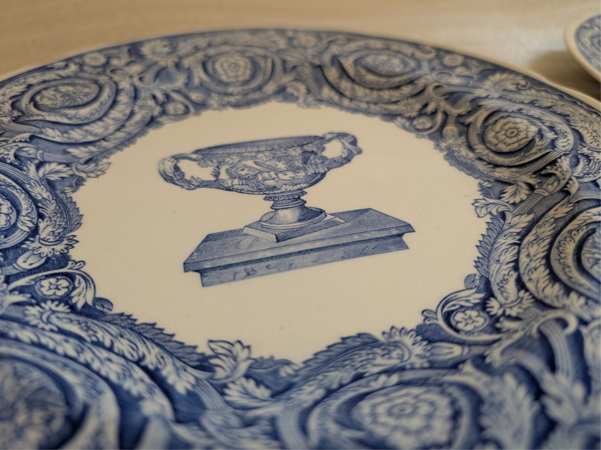Blue-and-white dinner plate center design with urn illustration and blue scrollwork.