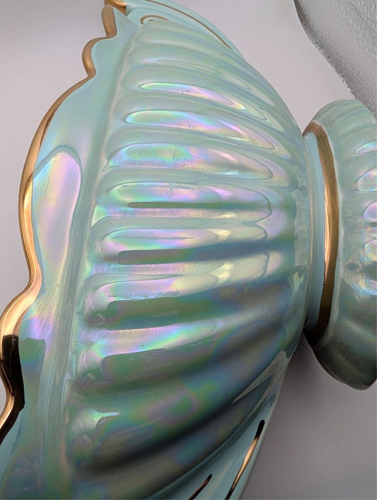 Iridescent oval bowl with gold-toned handle and scalloped rim edge, blue-green