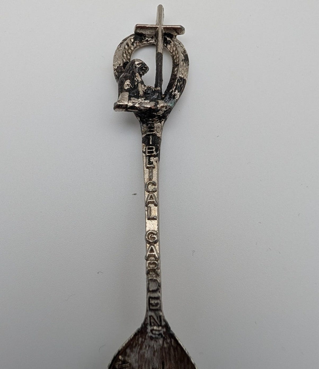 Souvenir spoon upright view with ornate loop handle and engraved vertical lettering