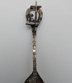 Souvenir spoon upright view with ornate loop handle and engraved vertical lettering