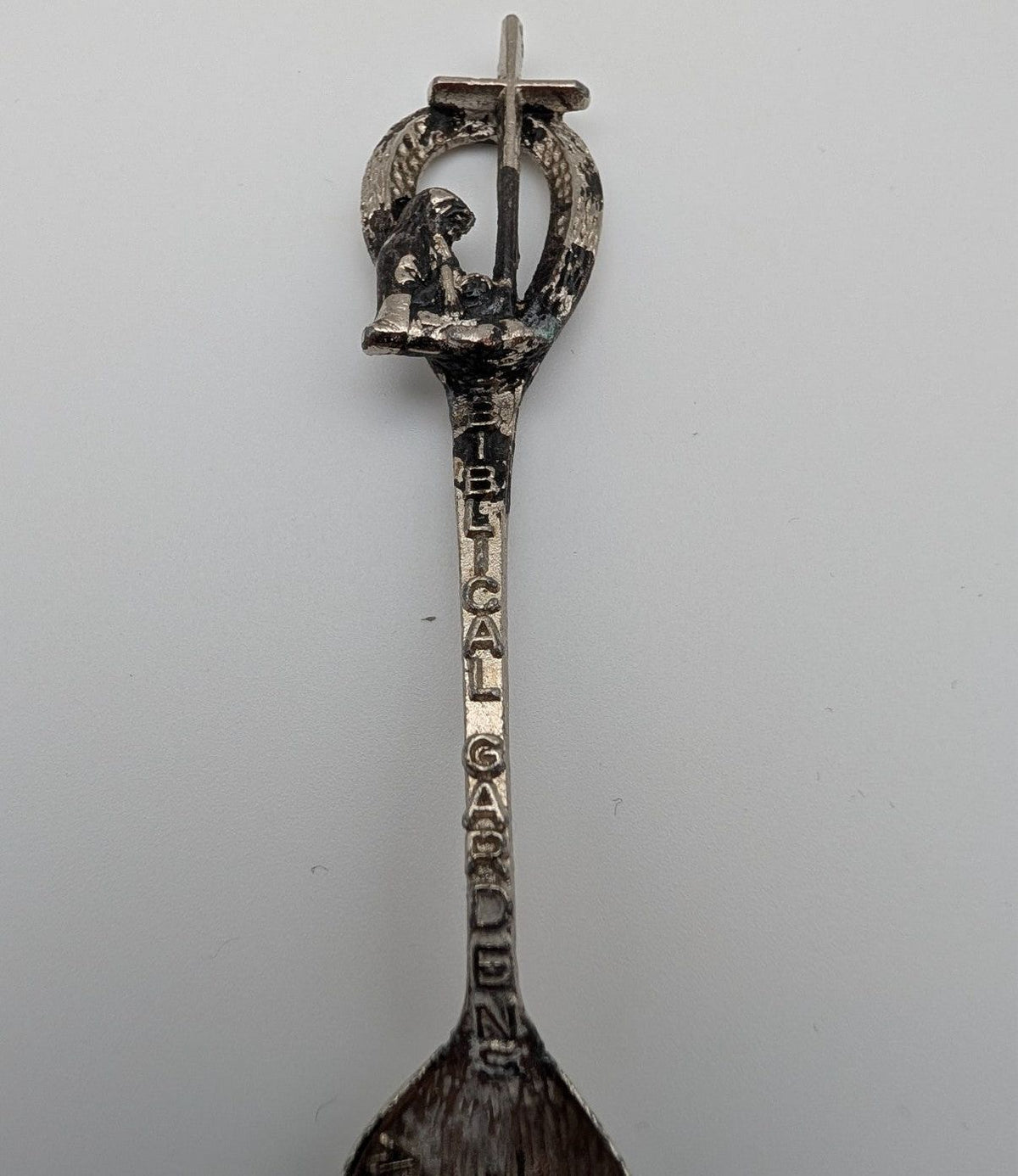 Souvenir spoon upright view with ornate loop handle and engraved vertical lettering