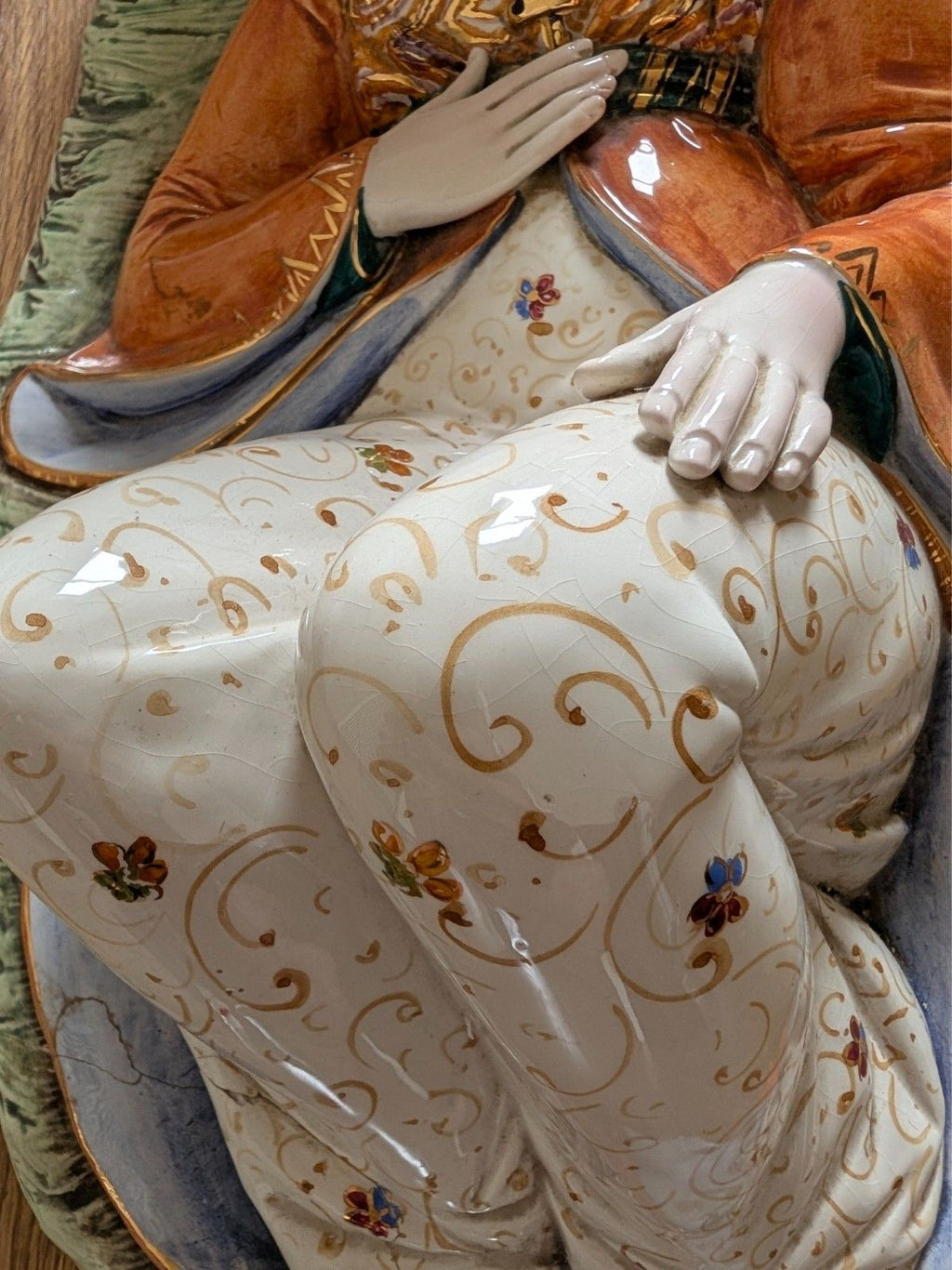 Porcelain sultan figurine with clasped hands and white robe with gold swirl and flower motifs
