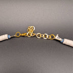 Gold clasp and chain on cream heishi beaded choker with blue accent bead