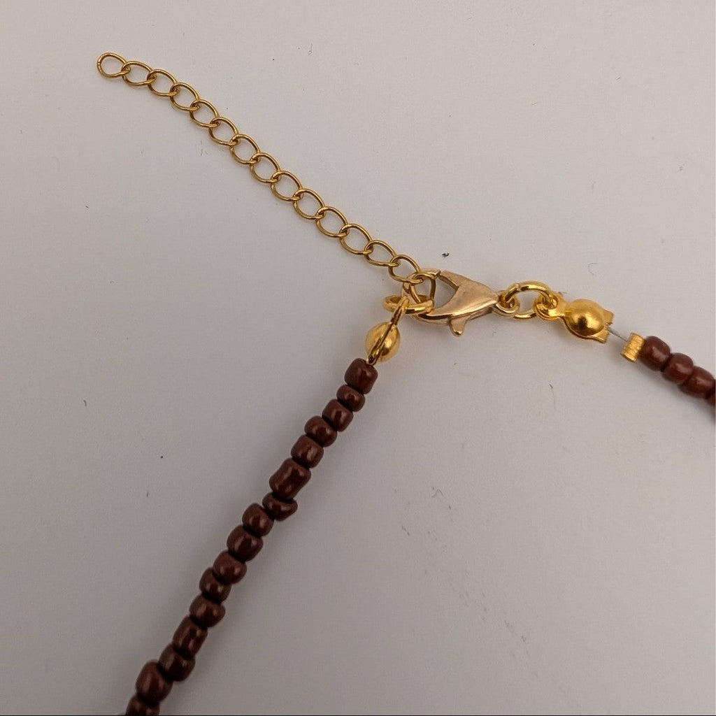 Adjustable gold-tone chain with lobster clasp and small amber beads at end