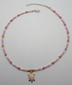 Pink beaded sea turtle choker necklace with small gold-tone turtle pendant and clasp