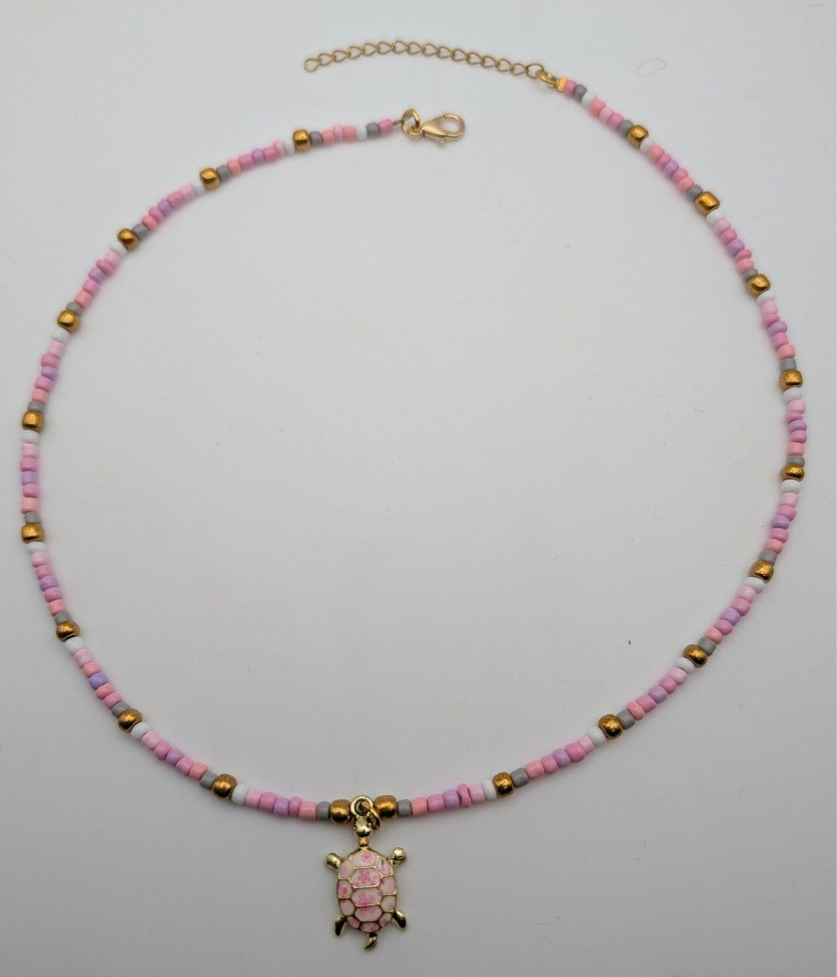 Pink beaded sea turtle choker necklace with small gold-tone turtle pendant and clasp