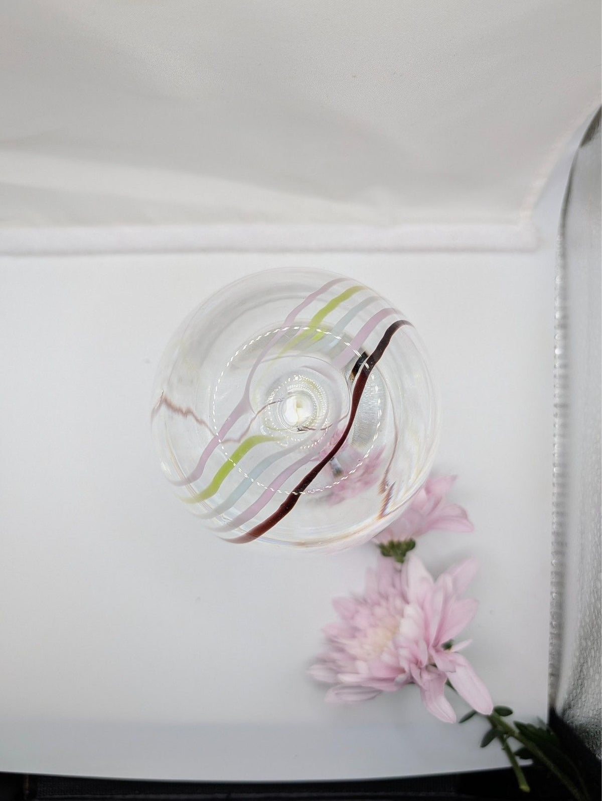 Clear glass bud vase with internal swirl and pink blossoms, close side view