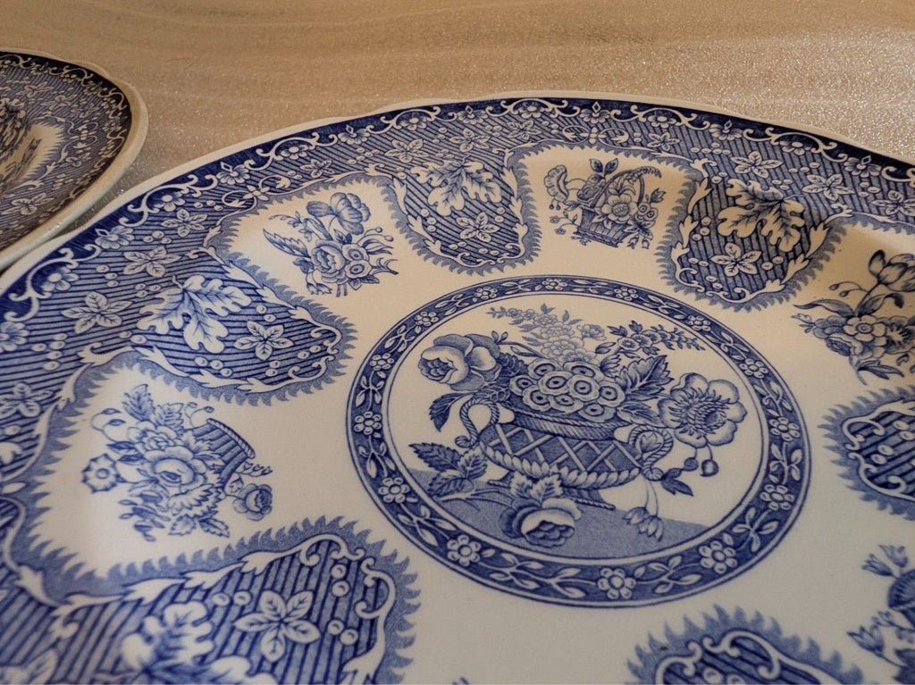 Blue-and-white dinner plate close-up: ornate border pattern around center floral motif