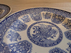 Blue-and-white dinner plate close-up: ornate border pattern around center floral motif