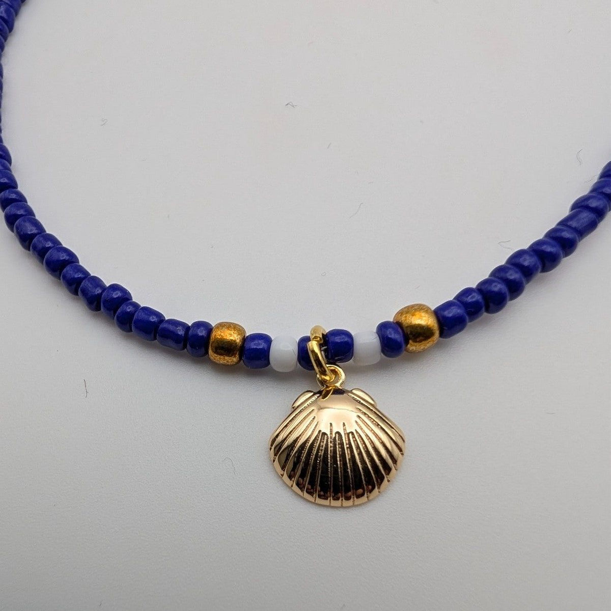 Blue glass beaded choker with gold seashell pendant and small spacer beads