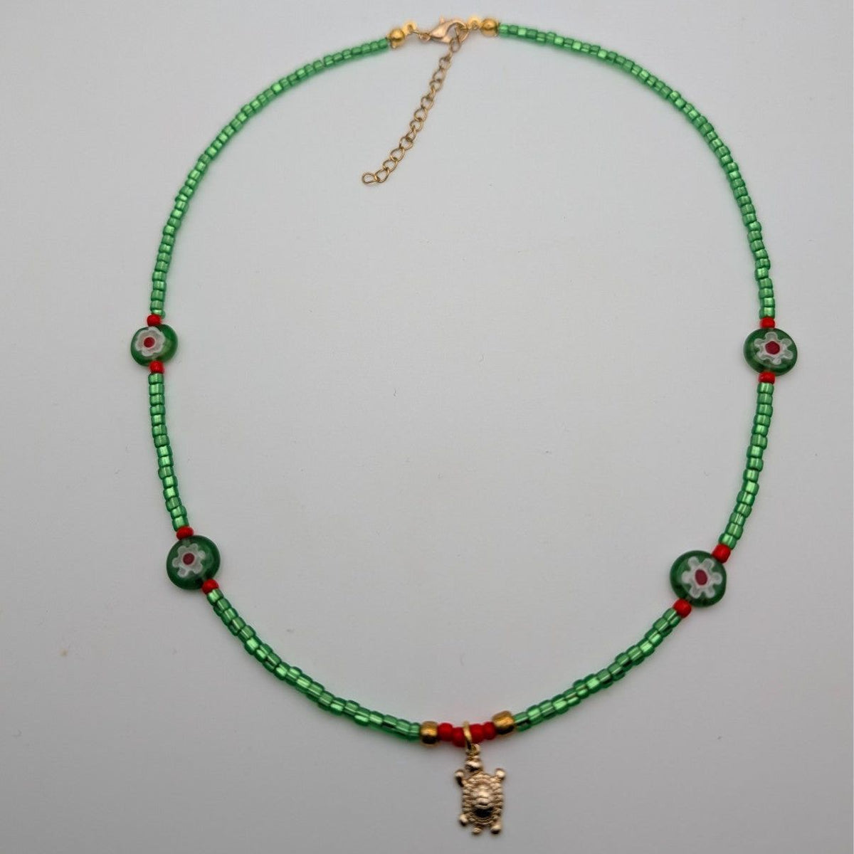 Green beaded choker necklace with turtle pendant, round millefiori bead accents