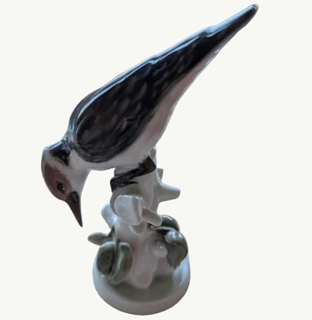 Hand-painted porcelain woodpecker figurine with dark body and white flowers on base