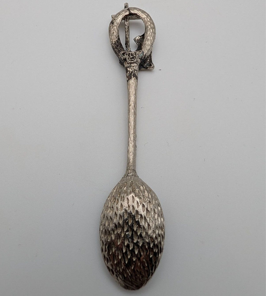 Souvenir spoon with loop handle and textured dark metal oval bowl