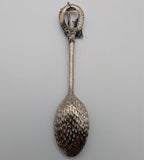 Souvenir spoon with loop handle and textured dark metal oval bowl