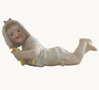 Porcelain baby figurine holding a lamb, reclining in white outfit
