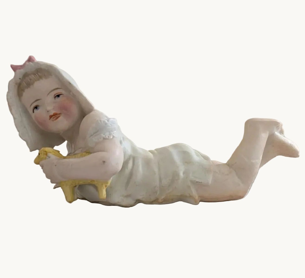 Porcelain baby figurine holding a lamb, reclining in white outfit