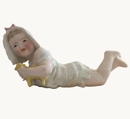 Porcelain baby figurine holding a lamb, reclining in white outfit