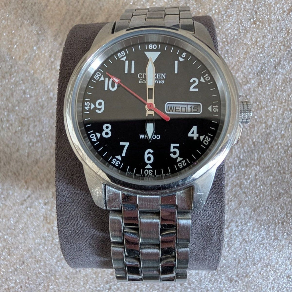 Military style watch close-up, black dial with red second hand and steel bracelet
