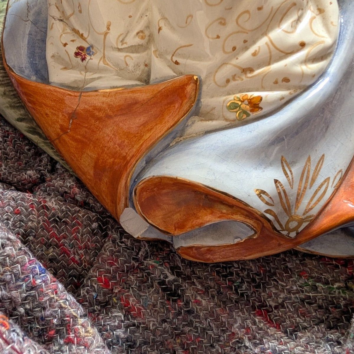 Porcelain figurine base with orange skirt trim and painted floral swirl accents
