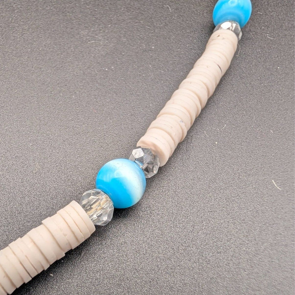 Beaded choker strand with cream heishi beads, blue beads, and silver spacer accents