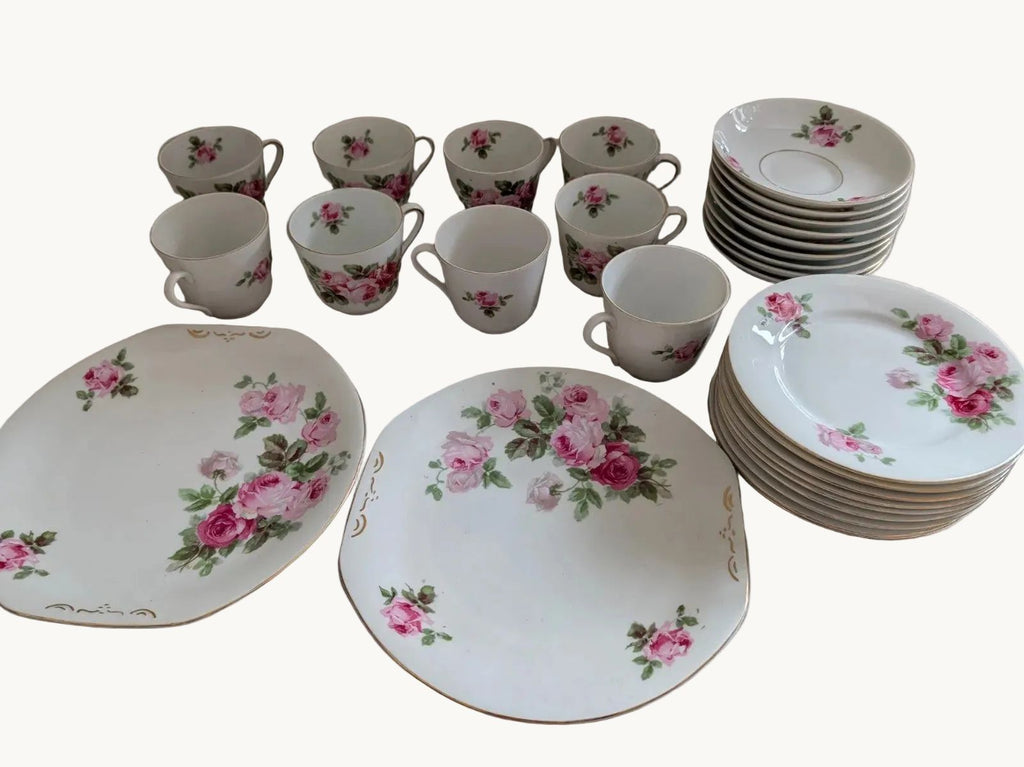 Porcelain tea and coffee set with pink rose pattern cups, saucers, and stacked plates