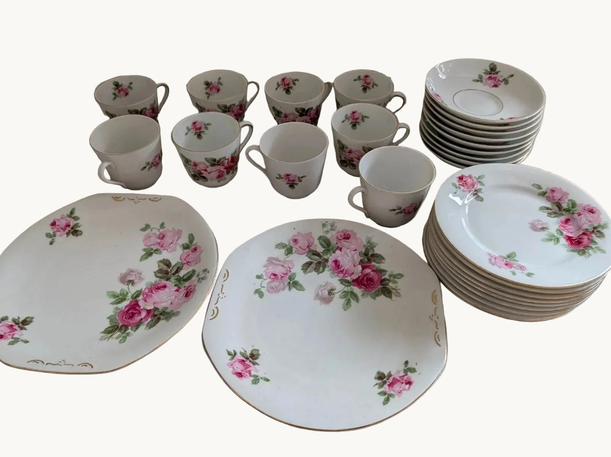 Porcelain tea and coffee set with pink rose pattern cups, saucers, and stacked plates