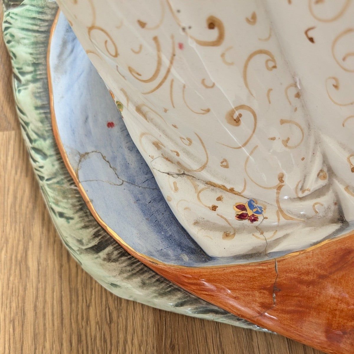 Porcelain robe detail with blue lining, gold edging, and floral swirl motifs