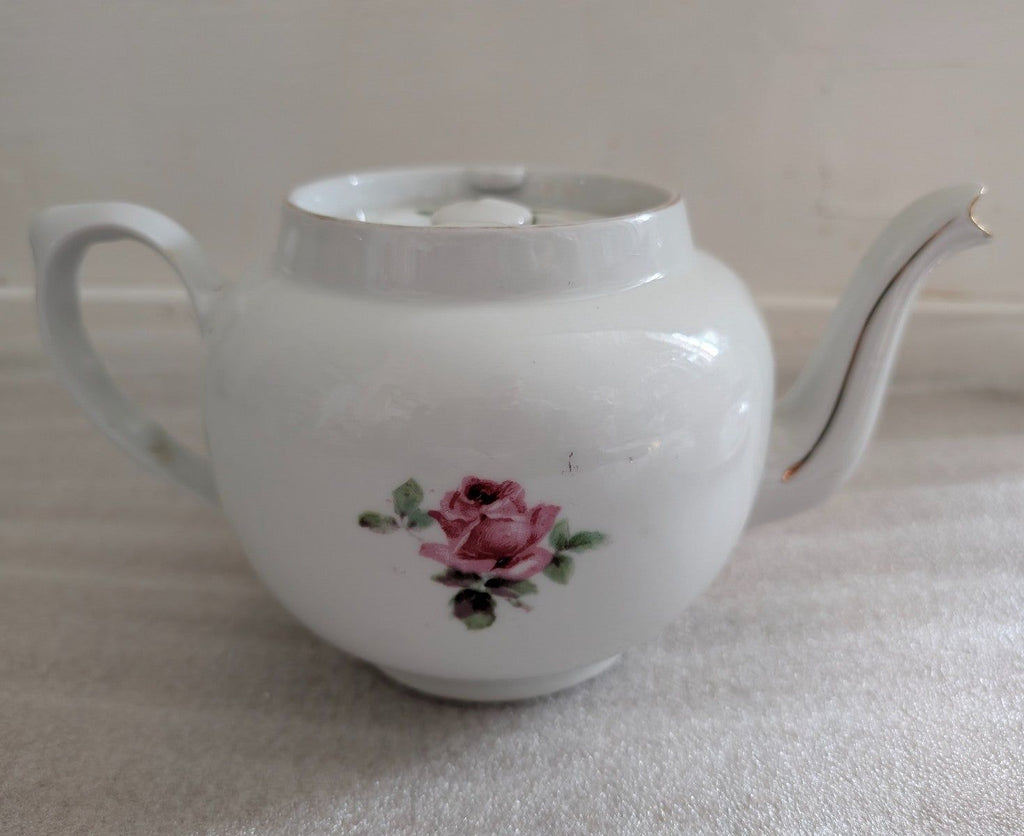 White porcelain sugar bowl with pink rose center, curved spout and handle