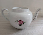 White porcelain sugar bowl with pink rose center, curved spout and handle
