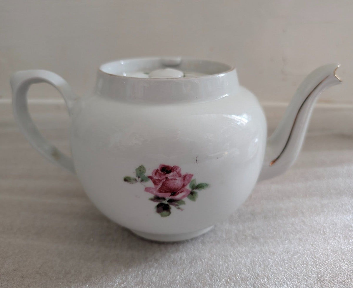 White porcelain sugar bowl with pink rose center, curved spout and handle