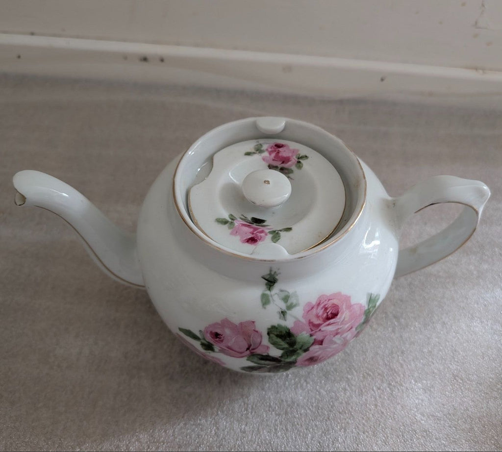 White porcelain teapot with pink rose and green leaf motif, lid and spout