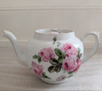 White porcelain teapot with pink rose bouquet, rounded body and side handle