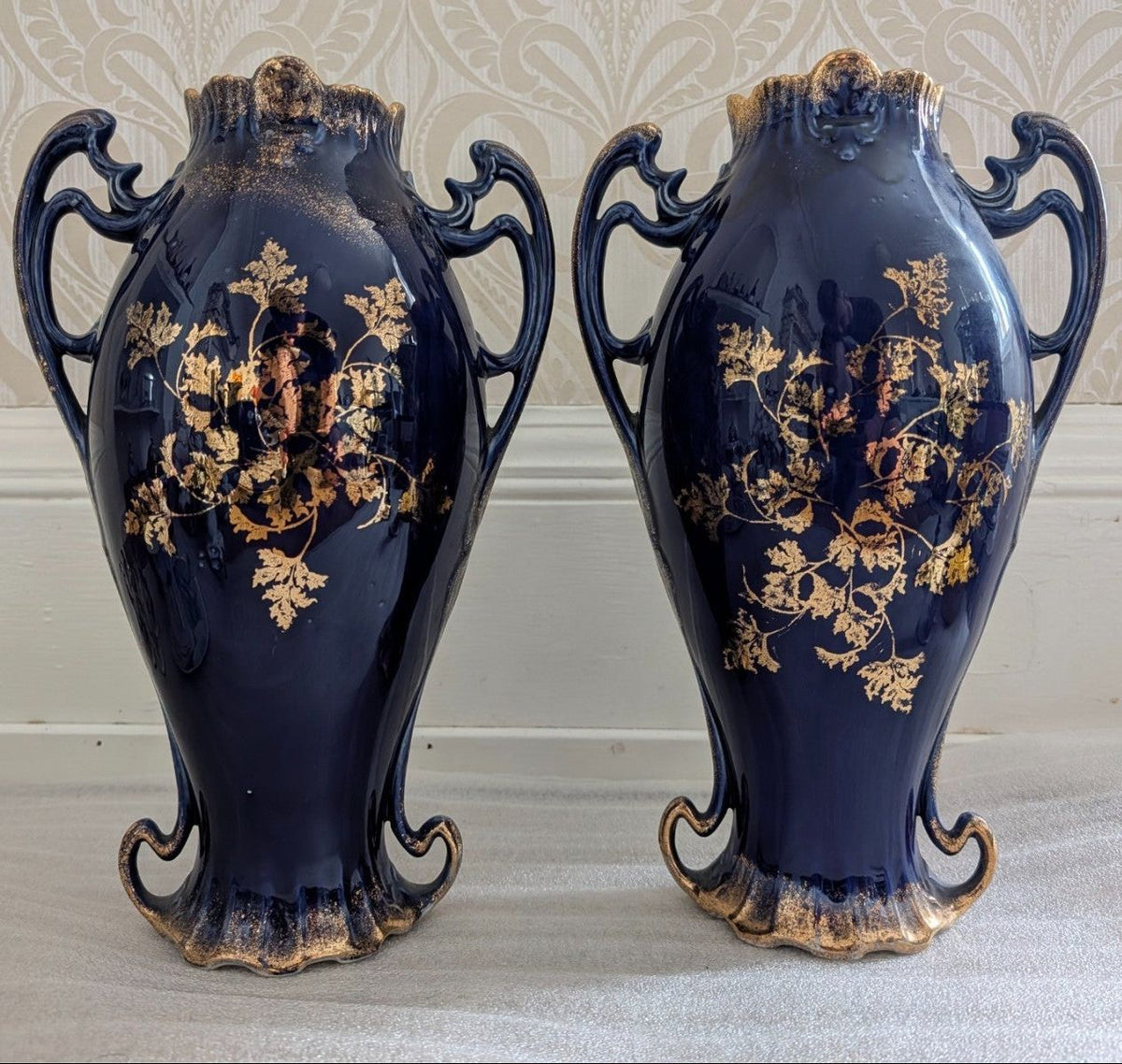 Pair of cobalt blue porcelain vases with ornate handles and gold floral medallion, Sevres-style