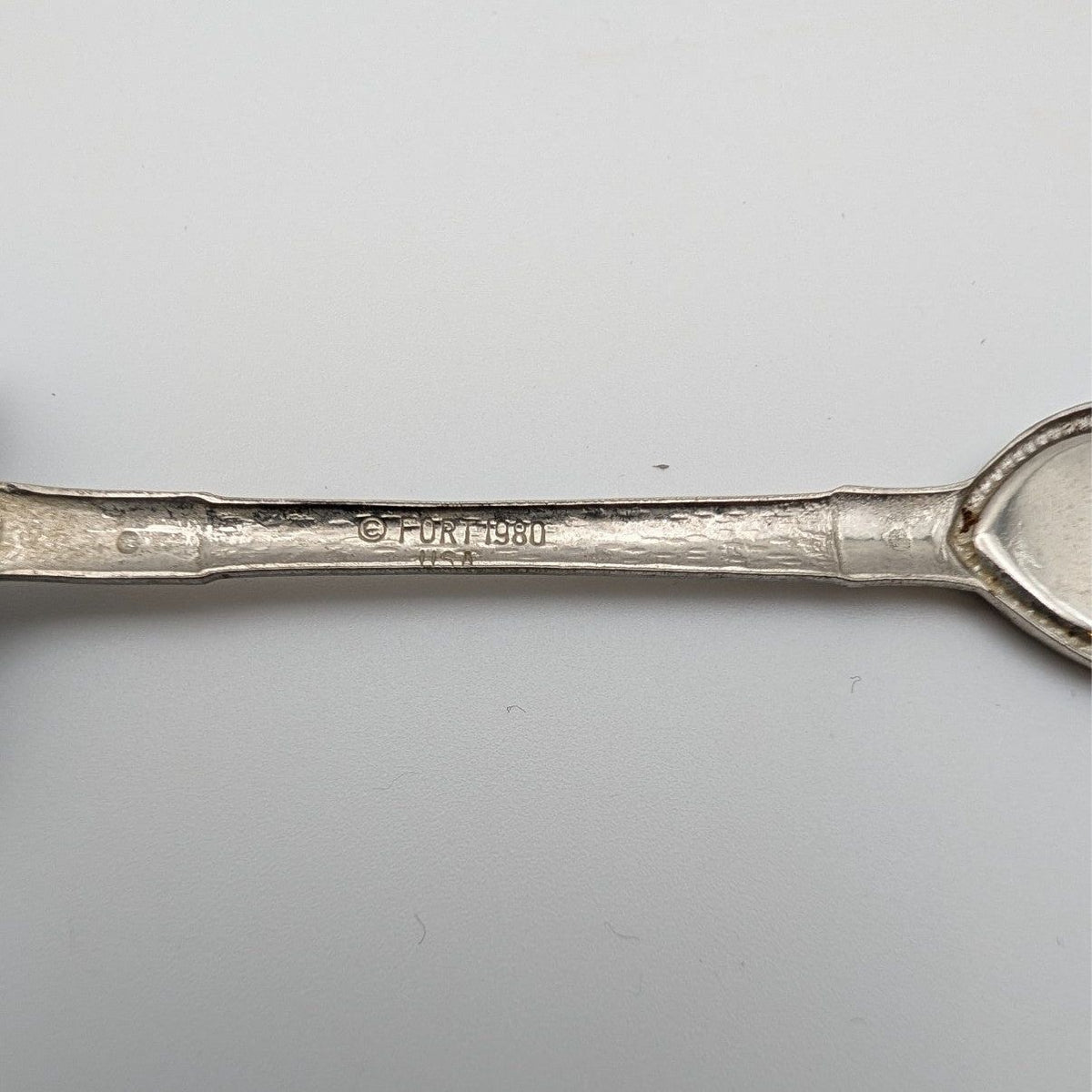 Engraved handle of shovel-shaped collector spoon marked “FORT INC 1980”