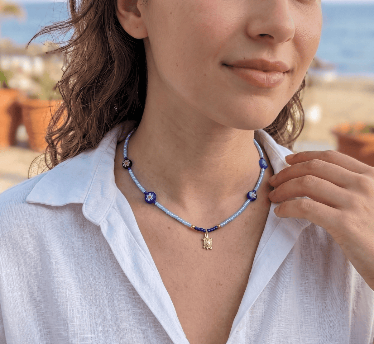 Beaded light blue choker with blue flower charms and small gold turtle pendant
